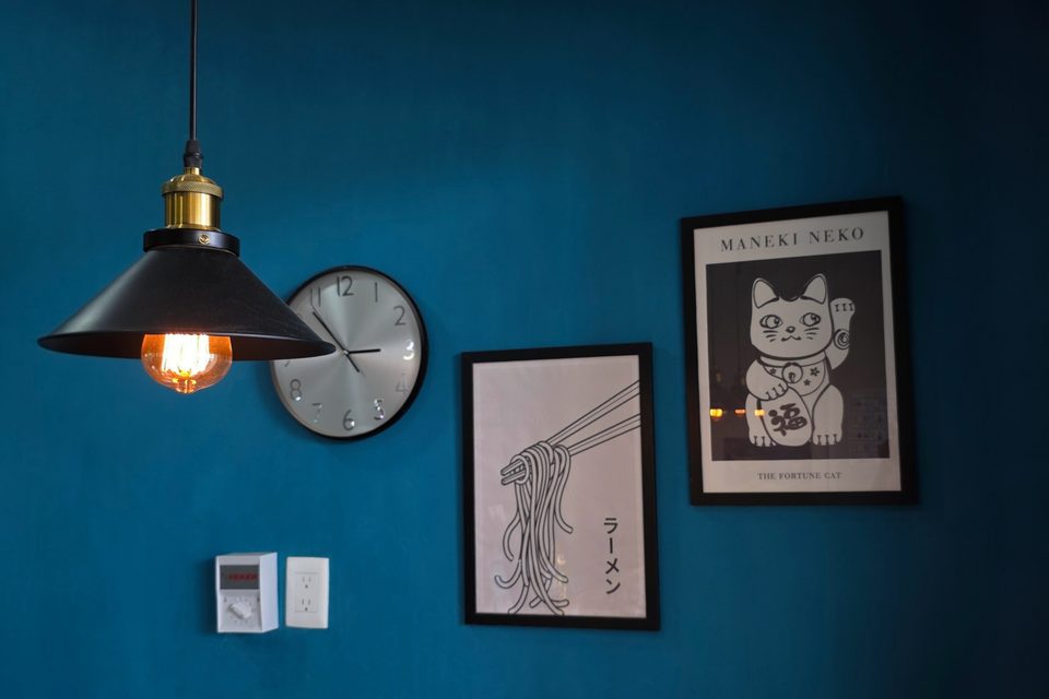 Blue interior wall with pendant lamp, clock and Japanese posters