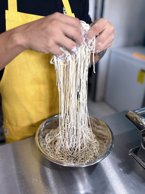 Hands pulling handmade noodles